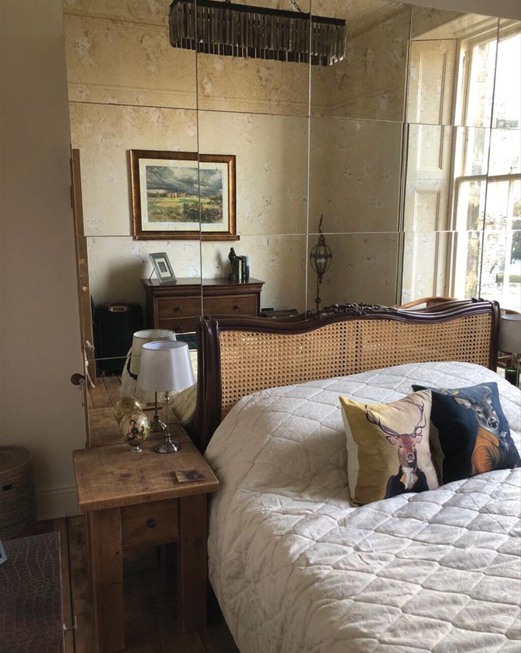 Een slaapkamer met een groot bed, een nachtkastje met een lamp, een kast en een ingelijst schilderij aan de muur.