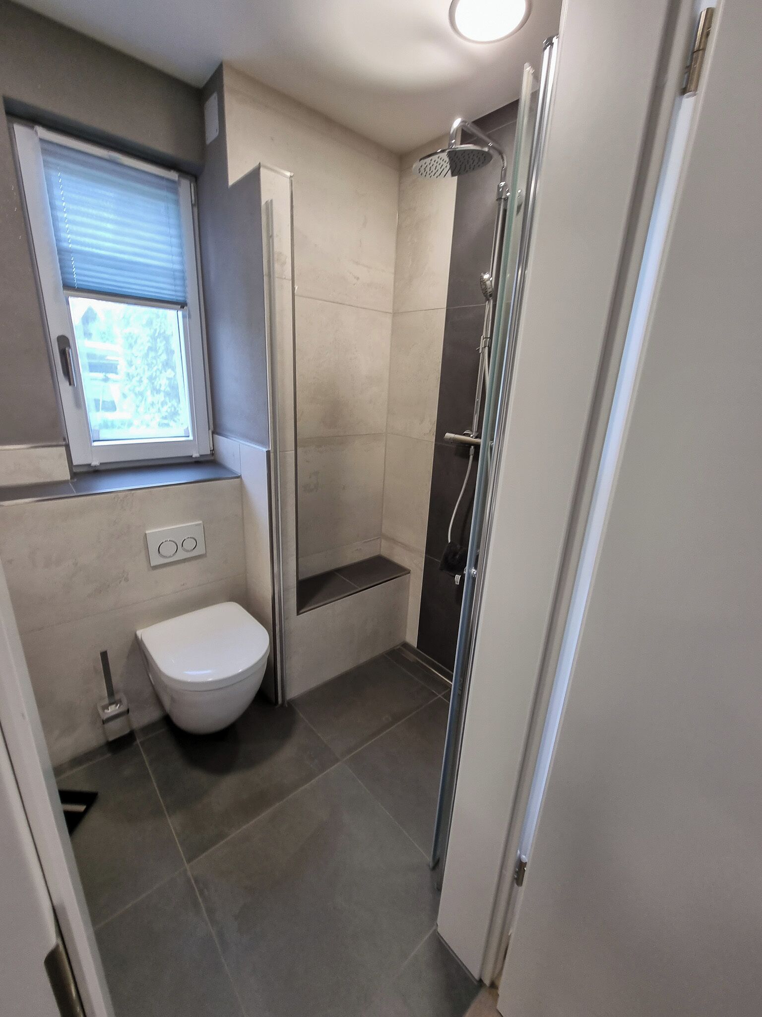 Ein modernes Badezimmer mit Toilette, Dusche und Fenster.