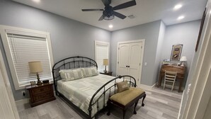 A bedroom with a bed, bedside tables, a desk, and a chair. - 2 bed, 2 bath cabin located in the country just west of College Station.   (Caldwell)