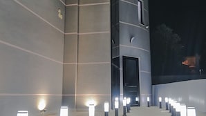 A modern building with a series of evenly spaced bollards along a wide, open walkway. - Vullkan Hotel (Ksamil)