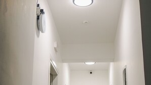A narrow, well-lit hallway with white walls, a ceiling fan, and a fire alarm. - Vullkan Hotel (Ksamil)