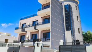 A modern multi-story building with balconies, large windows, and a curved corner section. - Vullkan Hotel (Ksamil)