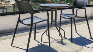 A terrace with two chairs and a table, overlooking a cityscape with buildings and mountains. - Vullkan Hotel (Ksamil)
