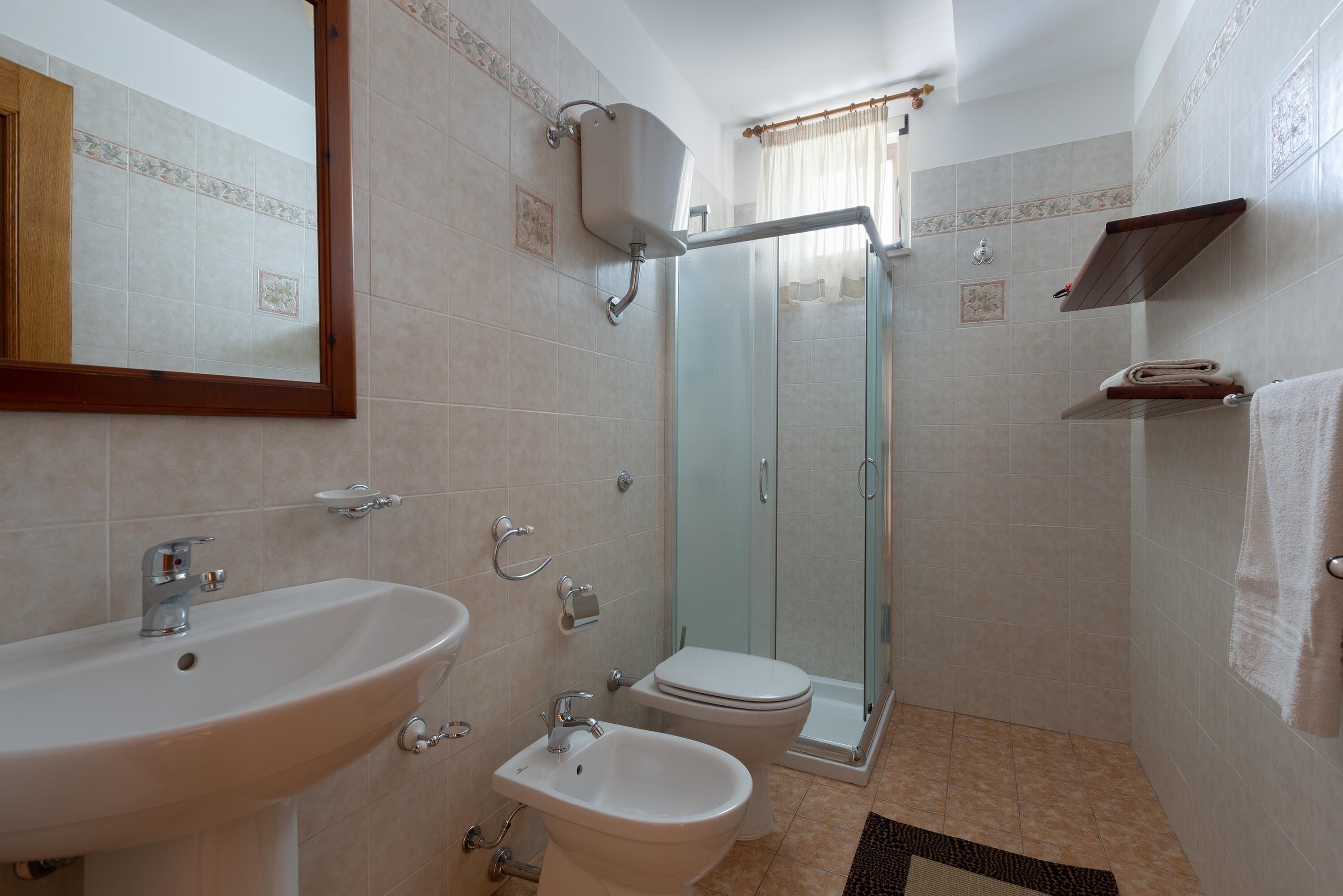Ein Badezimmer mit Waschbecken, Bidet, Toilette und Duschkabine aus Glas.