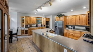 A spacious kitchen with wooden cabinets, stainless steel appliances, and a large island with a sink. - 4-Bedroom Mountain House w/Golf Course View, Hot Tub, Pool Table, & Foosball! (Whittier)
