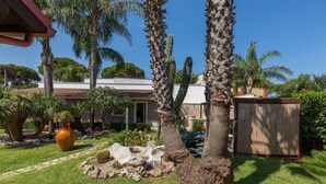A well-maintained garden with palm trees, a cactus, and a large vase.
