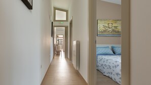 A hallway leading to a bedroom with a bed, a chair, and a radiator.