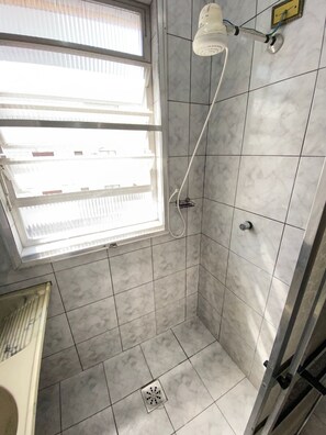 Shower area features a tiled floor and walls, a window, and a wall-mounted shower head.