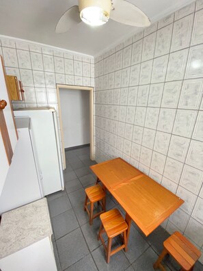 Enjoy meals in this kitchen with a refrigerator, dining table, and stools.