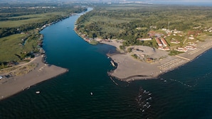 Vue aérienne d’une zone côtière avec une rivière, une plage et des immeubles résidentiels.