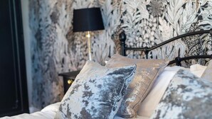 A bed with patterned pillows and a black lamp beside it.