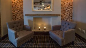 A room with a fireplace, two armchairs, a mirror, and a log wall.