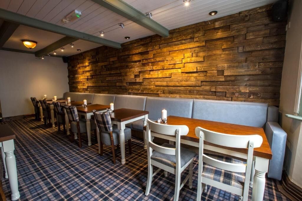 A restaurant interior with a wooden wall, checkered floor, and a seating area with tables and chairs.