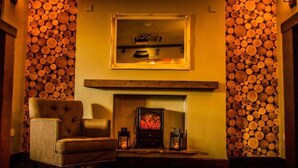 A cozy room with a fireplace, a framed picture on the wall, and a chair.