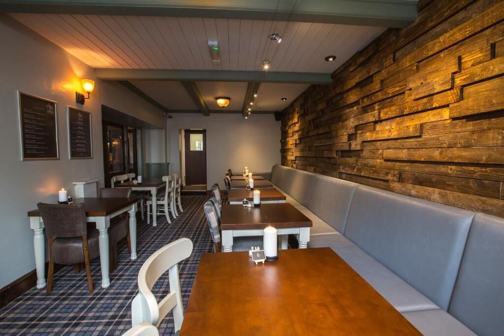 Un restaurante con paredes, mesas y bancos de madera.