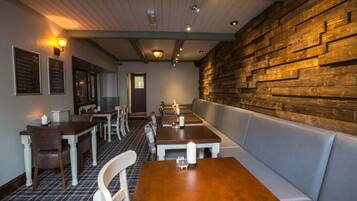 Un restaurante con paredes, mesas y bancos de madera.