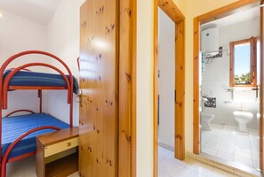 Ein Zimmer mit Etagenbett, Holzschrank und einem Badezimmer mit zwei Toiletten und einer Dusche.