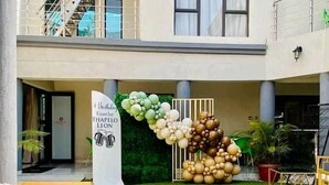 Un patio de hotel con asientos al aire libre, un arco decorativo y un cartel que dice 'Brindisi Toast for Thapelo Leonz'.