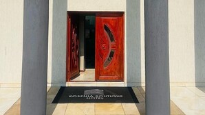Entrada de hotel con puertas dobles, felpudo negro y ventana de vidrio arriba.
