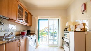 A kitchen with wooden cabinets, a washing machine, a microwave, and a dining area with a table and chairs.