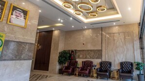 A lobby with a marble floor, a reception desk, and a seating area with leather chairs. - EMAAR INTERNATIONAL (Makkah)
