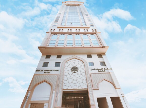 The exterior of the Emaar International Hotel with a prominent tower, large windows, and a decorative entrance.