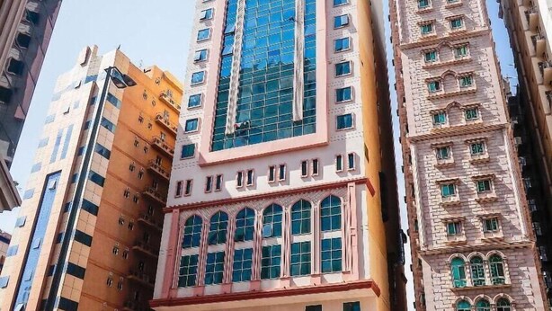 A tall building with a modern glass facade and traditional architectural elements. - EMAAR INTERNATIONAL (Makkah)