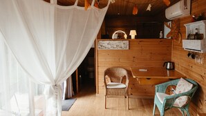 A cozy room with a wicker chair, a table, and a wooden cabinet. - Casa Rural Can Caponet (Llica d'Amunt)