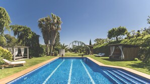 A rectangular swimming pool with clear blue water, surrounded by a well-maintained lawn and trees. - Casa Rural Can Caponet (Llica d'Amunt)