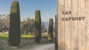A wooden structure with the text "CAN CAPONET" and a gravel path leading to it. - Casa Rural Can Caponet (Llica d'Amunt)