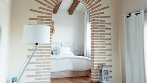 A staircase leading to a bedroom with a white bed, a lamp, and a small lantern. - Casa Rural Can Caponet (Llica d'Amunt)