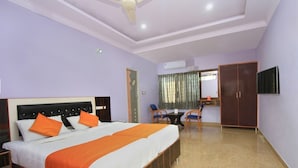 Ein Hotelzimmer mit Bett, Schreibtisch, Stuhl, Kleiderschrank und Fernseher.