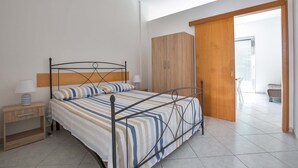 Une chambre à coucher avec un lit, une armoire en bois, une table de chevet et un luminaire vert suspendu au plafond.