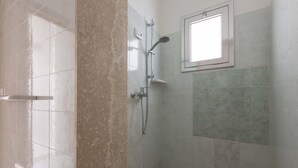 Une salle de bain avec une douche, une fenêtre et des murs carrelés.