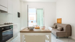 Une cuisine compacte dotée d’un four encastré, d’une table à manger avec des chaises et d’un canapé placé dans un coin.