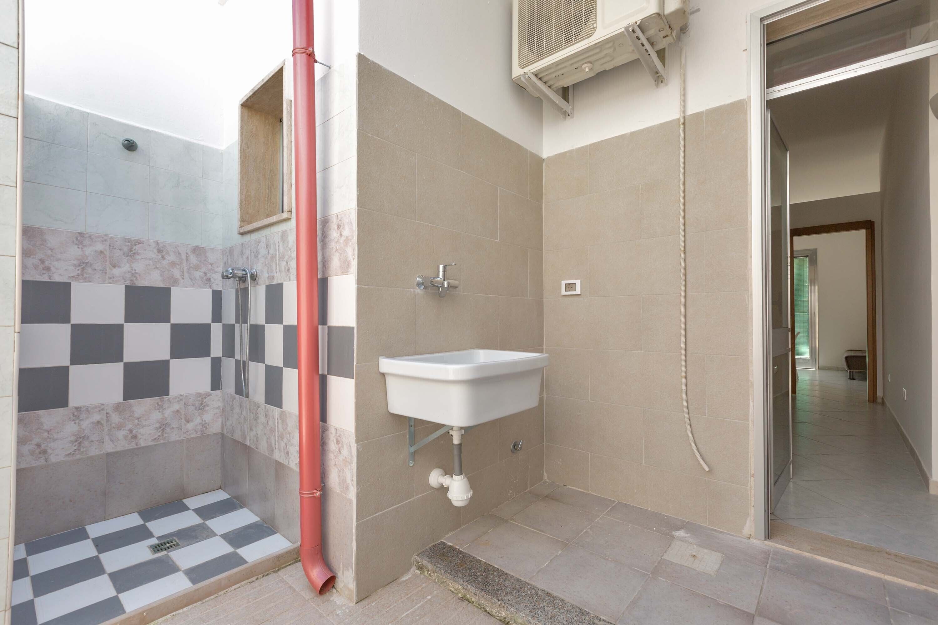 Ein Badezimmer mit Schachbrettboden, einem Waschbecken und einer Dusche.