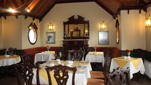 Un espace repas agrémenté de poutres en bois, de tables rondes et de chaises.