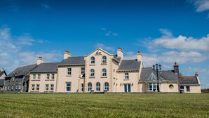 Un grand immeuble à plusieurs étages, doté d’une façade symétrique, de nombreuses cheminées et d’une entrée imposante.