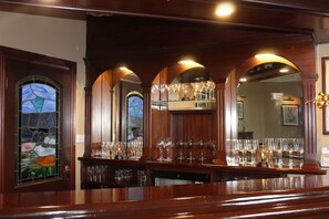 A bar area with wooden paneling, a stained glass window, and a mirror reflecting the interior. - Aranview Country House (DOOLIN)
