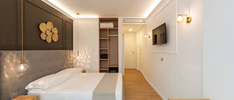 Quarto moderno com cama, mesas de cabeceira, guarda-roupa e televisão na parede.