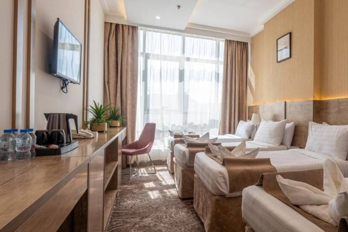 A hotel room with a bed, a desk, a chair, a TV, and a window with curtains.