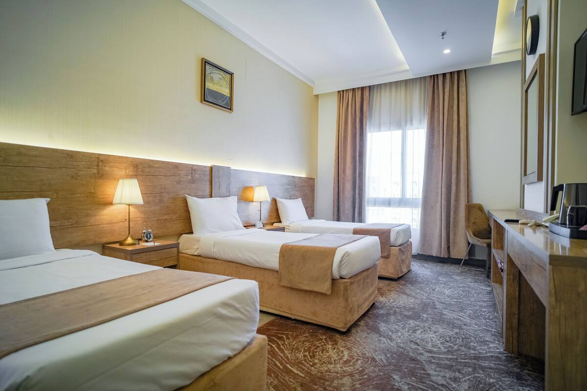 A hotel room with two beds, a desk, and a chair.