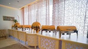 Disposição de buffet com várias estações de comida e uma planta decorativa.