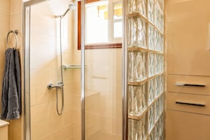 A shower with a glass door, a towel ring, and a glass shelf.