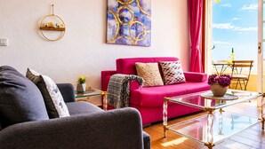 Ein Wohnzimmer mit einem roten Sofa, einem Glastisch und einem Bild an der Wand.