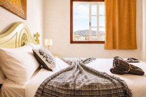 A hotel room with a bed, a view of the city through a window, and a curtain.