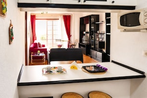 A compact kitchen with a dining area, a red sofa, and a small table with cups and a tray. - Comfy Home in Los Cristianos (Arona)