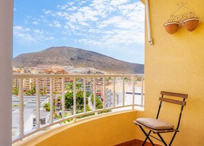 A balcony with a view of a mountain, a chair, and a wall-mounted light fixture. - Comfy Home in Los Cristianos (Arona)