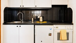 Eine kleine Küche mit Spüle, Wasserkocher und einem Backofen.
