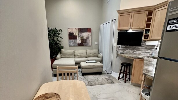 Una cocina compacta con refrigerador integrado, microondas y comedor con mesa y banco de madera.